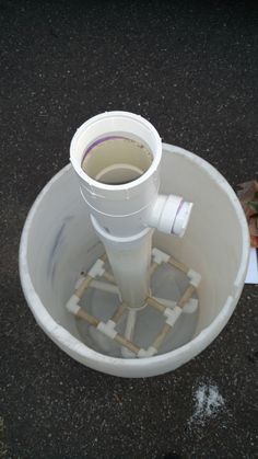 a white bucket filled with water sitting on top of a black floor next to a pile of paper towels