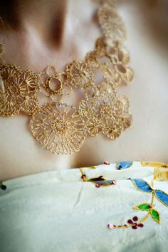 a close up of a woman's neck wearing a necklace with gold filigrees