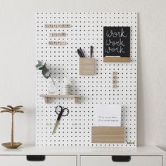 a white pegboard mounted to the side of a wall with office supplies on it