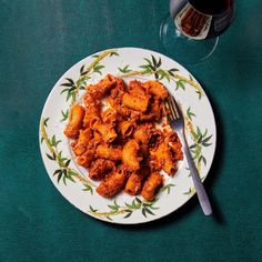 a white plate topped with pasta next to a glass of red wine and a fork