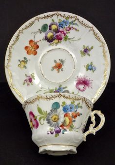 an antique tea cup and saucer decorated with flowers