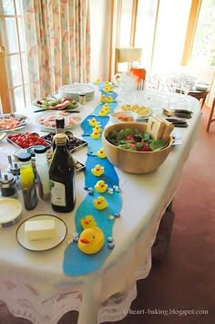 a long table covered in plates and bowls with food on it, including rubber ducks