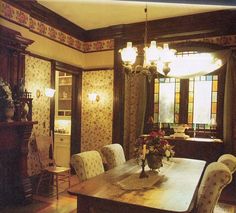 the dining room table is surrounded by white chairs and floral wallpaper, along with an ornate chandelier