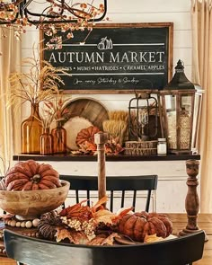 an autumn market display with pumpkins, bread and other items on a table in front of a sign