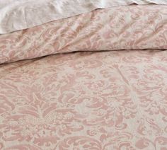 a bed with pink and white bedspread on it's side next to a pillow