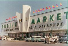 people walking in front of a market with cars parked outside