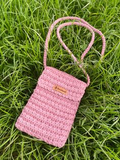 a pink crocheted cell phone case laying in the grass