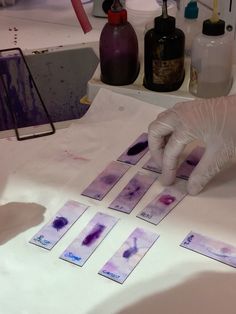 a person in white gloves is doing something on a table with purple and blue ink