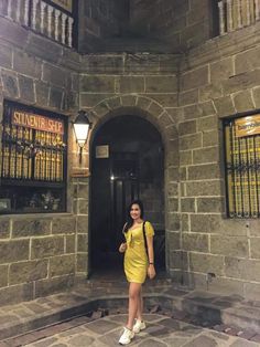 a woman standing in front of a stone building