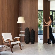 a woman standing in a living room next to a chair