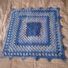 a blue and white crocheted afghan on a bed