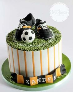 a soccer themed birthday cake with shoes and a ball on the top, decorated with grass