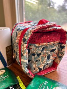 a bag sitting on top of a wooden table next to a cup