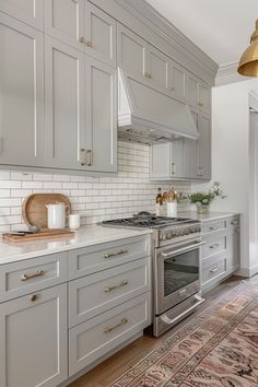 a kitchen with white cabinets and gold hardware on the counter tops, along with an area rug