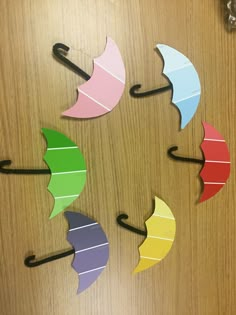 four umbrellas are arranged in the shape of a circle on a wooden surface with hooks