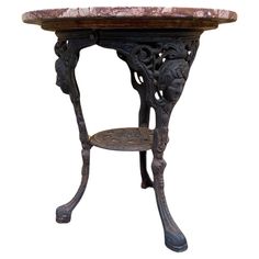 an old table with a marble top and metal legs