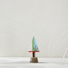 a small green christmas tree sitting on top of a wooden table next to a white wall