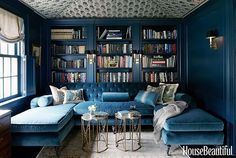 an image of a living room with bookshelves on the wall and blue couches