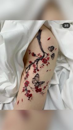 a woman's arm with red flowers and butterflies on it