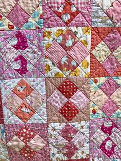 a pink and red patchwork quilt with hearts on the center is shown in close up