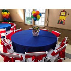 a blue table with red, white and blue chairs in front of balloons on the wall