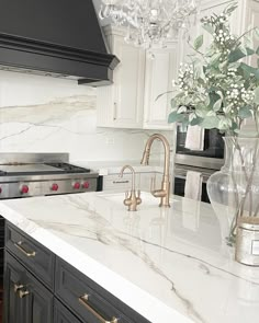 a kitchen with marble counter tops and white cabinets, black appliances and a chandelier hanging from the ceiling