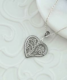 Introducing our handcrafted filigree art Tree of Life in Heart Figure Women's Silver Pendant Necklace! This beautiful piece features a stunning tree of life design within a heart-shaped pendant, handcrafted with the utmost care and attention to detail. Made with high-quality silver, the pendant measures 1.30 inches in height and 0.90 inches in width, while the 20-inch silver chain ensures a comfortable and adjustable fit. Additionally, this necklace comes with a silver polish cloth and a luxurio Heart-shaped Filigree Jewelry, Heart Shaped Filigree Jewelry, Heart Shaped Jewelry With Intricate Design For Valentine's Day, Heart-shaped Jewelry With Intricate Design For Valentine's Day, Heart Pendant Jewelry With Intricate Design For Valentine's Day, Handmade Heart Pendant Necklace For Mother's Day, Valentine's Day Heart Pendant With Intricate Design, Ornate Heart Charm Pendant Jewelry, Artisan Sterling Silver Heart Necklace