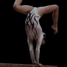 a person doing a handstand on the balance beam