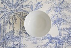 a white bowl sitting on top of a table next to a wallpapered wall