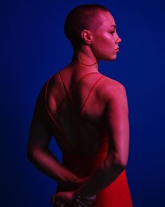 a woman in a red dress with her back turned to the camera, against a blue background