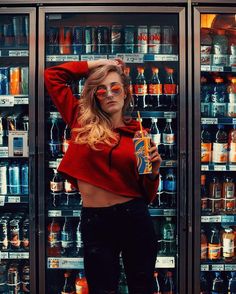 a woman standing in front of a refrigerator filled with drinks