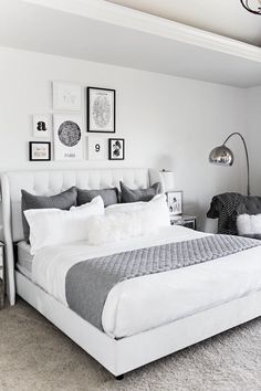 a bed with white sheets and pillows in a bedroom next to pictures on the wall