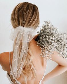 the back of a woman's head wearing a veil and flowers in her hair