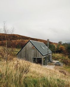 a small wooden building sitting on top of a grass covered hillside