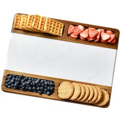 a wooden tray with waffles, blueberries, strawberries and other snacks