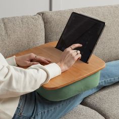 a person sitting on a couch with a laptop computer in their lap and pointing to the screen