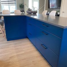 a kitchen with blue cabinets and counter tops in it's center island area, next to a television on the wall