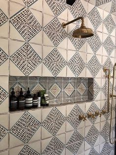 a bathroom with white and blue tiles on the wall, shower head and hand held soap dispenser