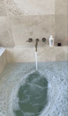 a bathtub filled with water next to a faucet