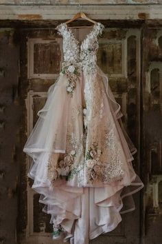 a dress hanging on a wooden door with flowers and leaves in the bottom layer, as if it were made out of tulle