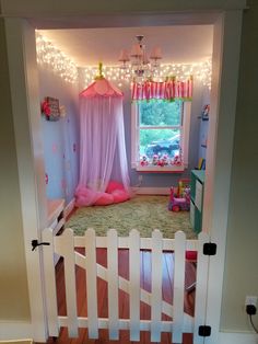 a bedroom with pink curtains and lights on the ceiling is shown through an open door