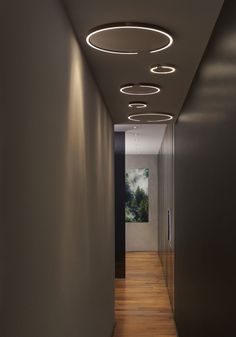 a long hallway with lights on the ceiling and wood flooring in front of it