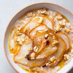 a bowl filled with oatmeal topped with sliced pears and walnuts