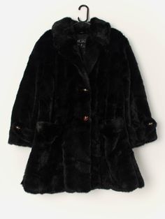 Vintage faux fur long coat in black. This stunning coat from the 1980s is in a stunning glossy black and features two large front hand pockets, stunning black and gold buttons, a soft lining in black and split hems. A lovely jacket that will keep you nice and snug in the colder months! Made from a soft, heavyweight material. Made in Italy.  Our recommended size: Medium to large  Label says: No size label Condition: Very good Material: No care label  Measurements in inches: Pit to pit: 23 Shoulders: 18 Front length: 34.5 Back length: 35 Sleeve length: 23.5 Hem unstretched: 26  We recommend that you compare our measurements to a similar item of your own to ensure good fit. Measurements are taken flat and doubled for waist and hip. Our items are vintage and may show signs of previous wear, et Evening Outerwear With Faux Fur Lining In Mink Color, Black Fur Coat For Evening In Fall, Formal Black Faux Fur Coat, Black Fur Lined Coat, Black Faux Fur Outerwear For Evening, Black Faux Fur Coat For Evening, Black Fur Coat With Faux Fur Lining For Party, Black Faux Fur Trim Outerwear For Evening, Black Formal Fur Coat With Faux Fur Trim