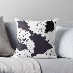 a black and white pillow sitting on top of a couch next to two gray pillows