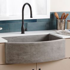 a kitchen sink made out of concrete in front of a counter top with utensils