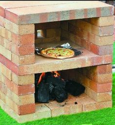 a pizza sitting on top of a brick oven in the middle of some green grass