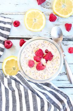 a bowl of oatmeal with raspberries and lemons on the side