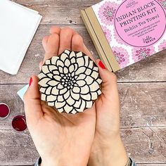 a person holding a small wooden object in their hands next to a book and glasses