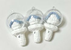 three crocheted ornaments in the shape of people wearing hats and holding umbrellas